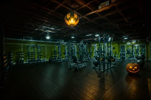 photo from pinterest of halloween-style interior designed (fitness gym interior) with dumbbell stand and crosstrainer and squat rack and bench press and exercise bicycle and dumbbell stand. . with yellow black balloons and lanterns and cobwebs and human skulls and skeletons sitting and standing and cobwebs and spiderwebs and glowing pumpkins. . cinematic photo, highly detailed, cinematic lighting, ultra-detailed, ultrarealistic, photorealism, 8k. trending on pinterest. halloween interior design style. masterpiece, cinematic light, ultrarealistic+, photorealistic+, 8k, raw photo, realistic, sharp focus on eyes, (symmetrical eyes), (intact eyes), hyperrealistic, highest quality, best quality, , highly detailed, masterpiece, best quality, extremely detailed 8k wallpaper, masterpiece, best quality, ultra-detailed, best shadow, detailed background, detailed face, detailed eyes, high contrast, best illumination, detailed face, dulux, caustic, dynamic angle, detailed glow. dramatic lighting. highly detailed, insanely detailed hair, symmetrical, intricate details, professionally retouched, 8k high definition. strong bokeh. award winning photo.